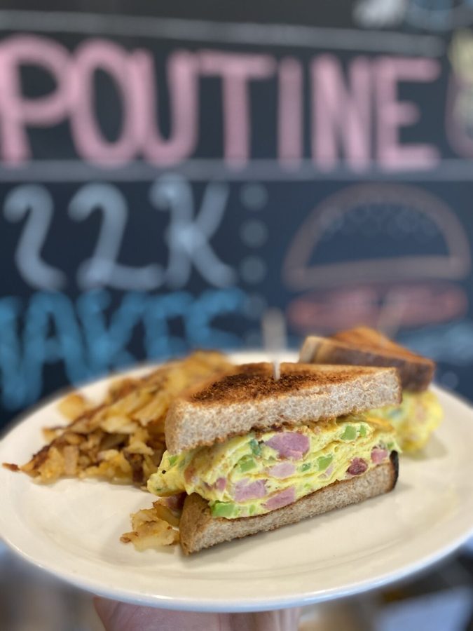 Toasted Western omelette sandwich with ham and green pepper, homefries on the plate